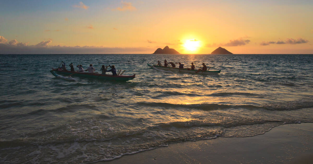 Two outrigger canoes paddle out from shore at sunrise in hawaii Royal Kona Coffee